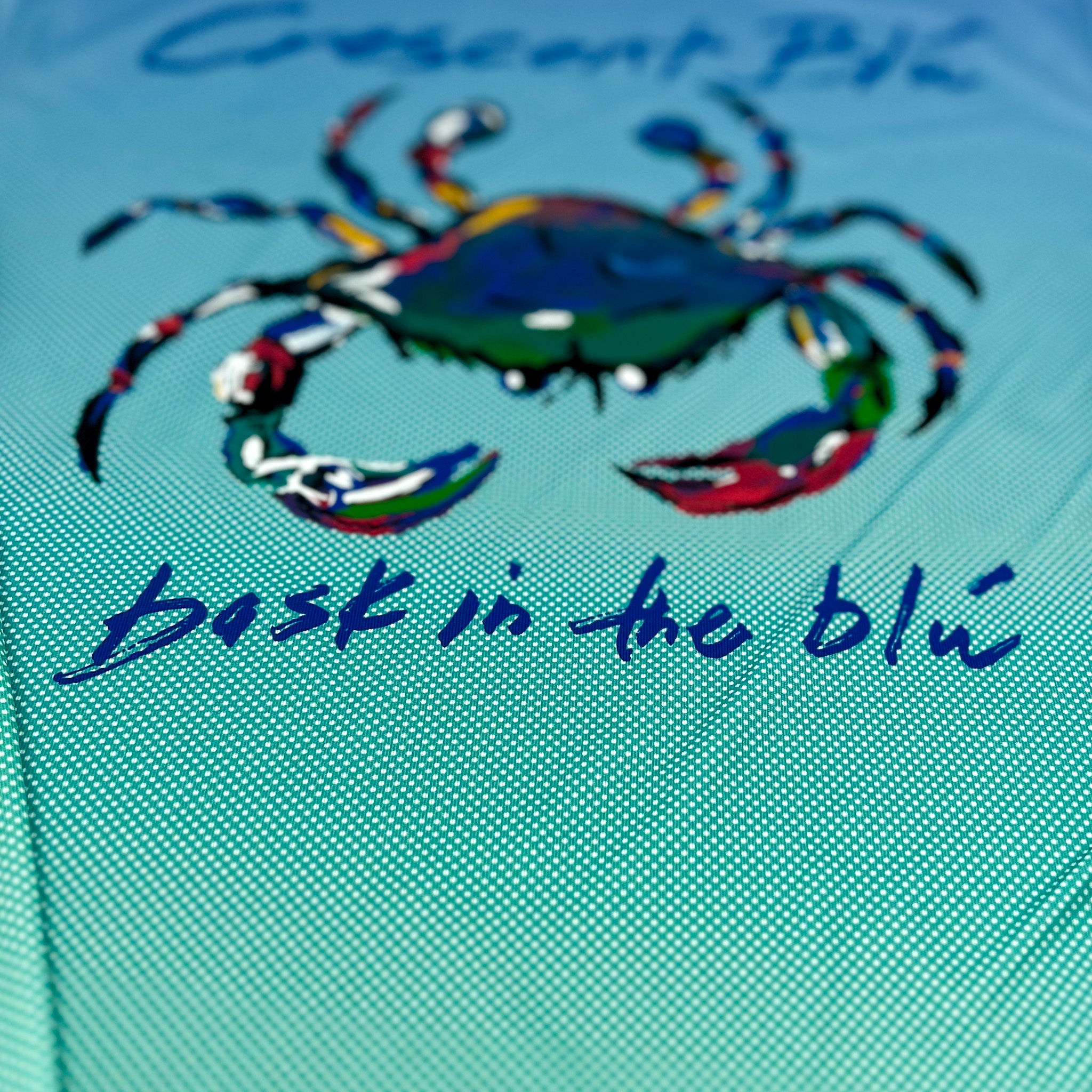 Close up of the back of a UPF dot gradient tee with the Crescent Blu crab logo on the back.