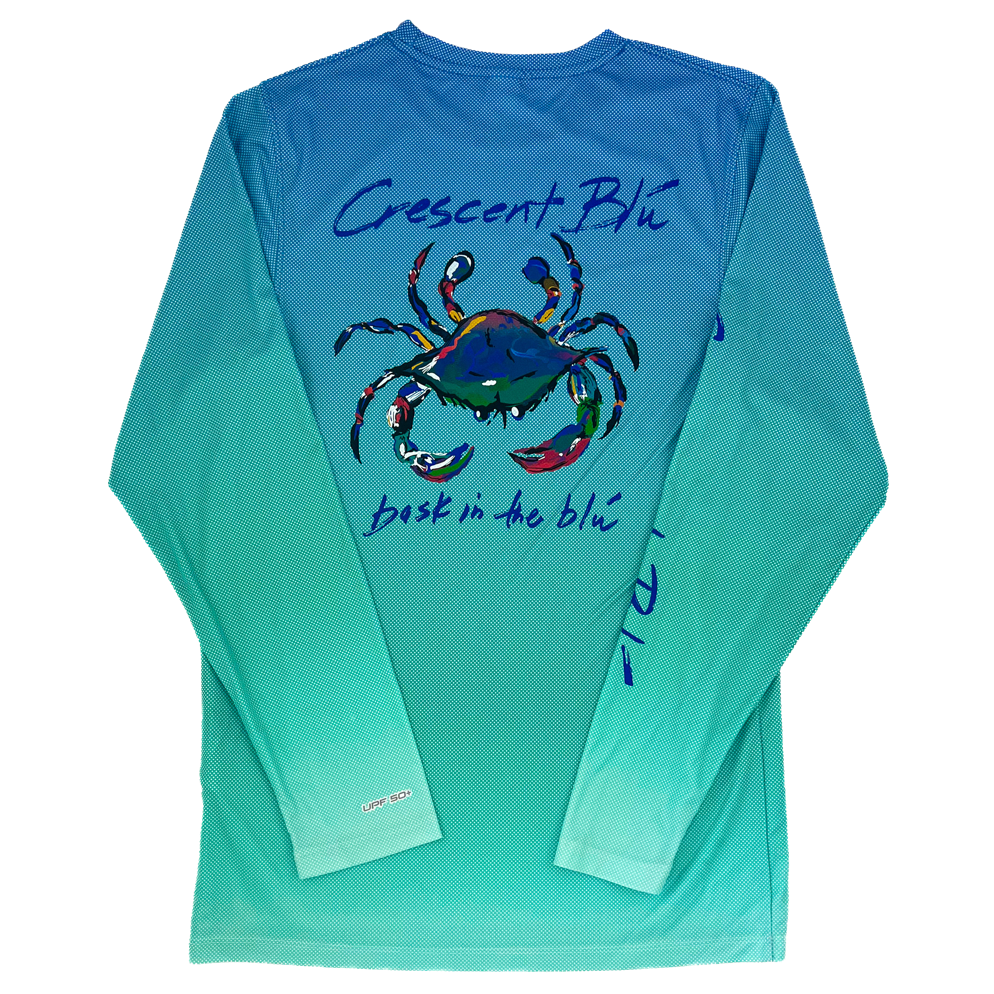 A blue crab is on the back of a long sleeve shirt.  The background of the shirt is  gradient color from  blue at the top to teal at the bottom. "Crescent Blu" is written above the crab and "bask in the blu" is written below it.