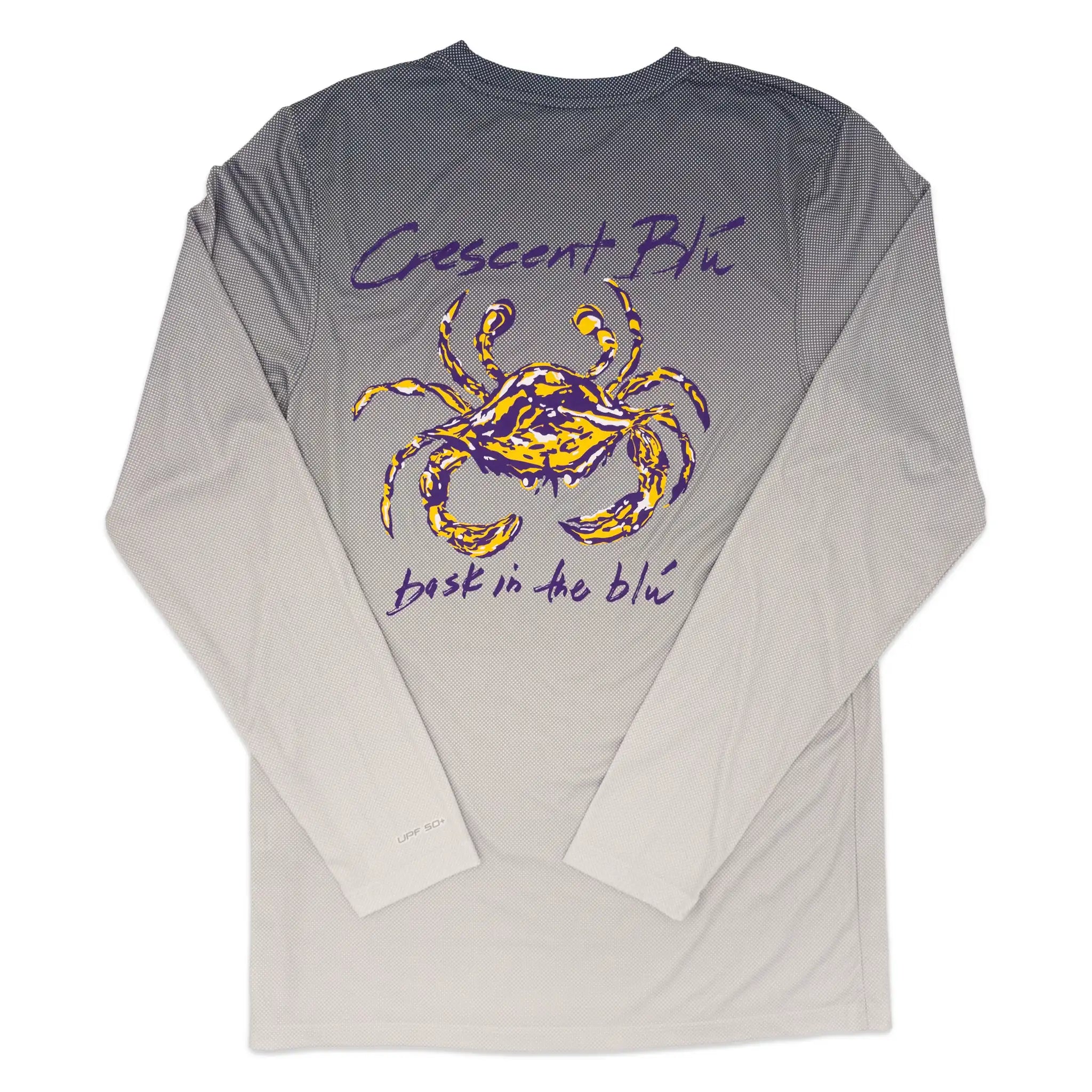 A long-sleeve UV t-shirt with a gray gradient body fading to white at the sleeves and hem, featuring a purple and gold crab graphic on the back with the text 'Crescent Blu' and 'bask in the blu'
