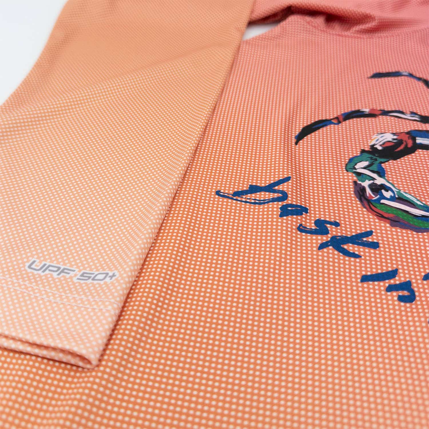 A zoomed in view of a gradient red orange pin dot long sleeve UPF sun shirt.