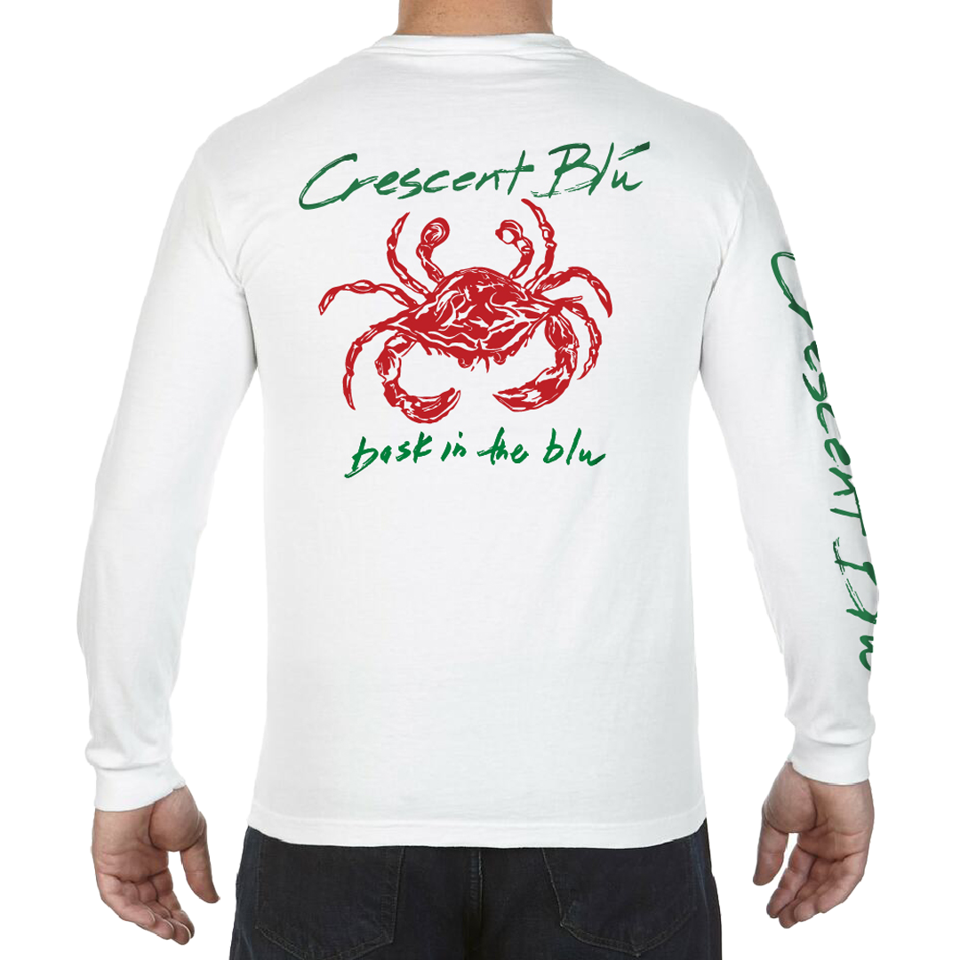 A man is wearing a long sleeve tee with a red crab on the back. Written in green above the crab is "Crescent Blu" and below the crab is written "bask in the blu".