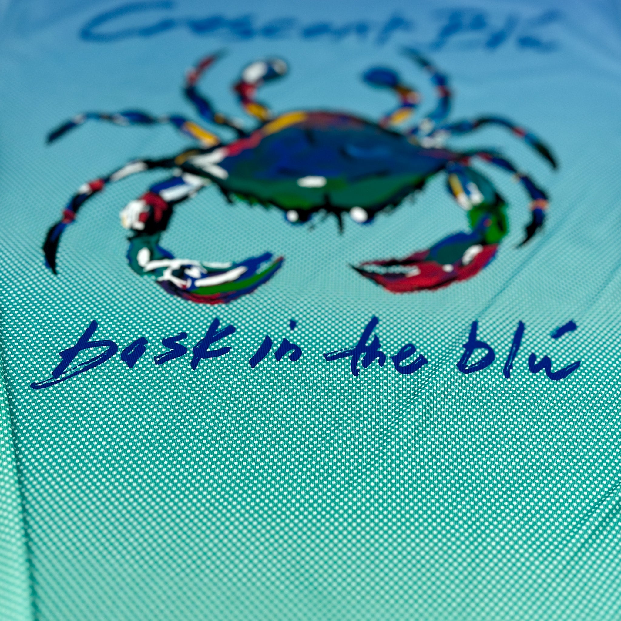 Close up of the back of a UPF dot gradient tee with the Crescent Blu crab logo on the back. 