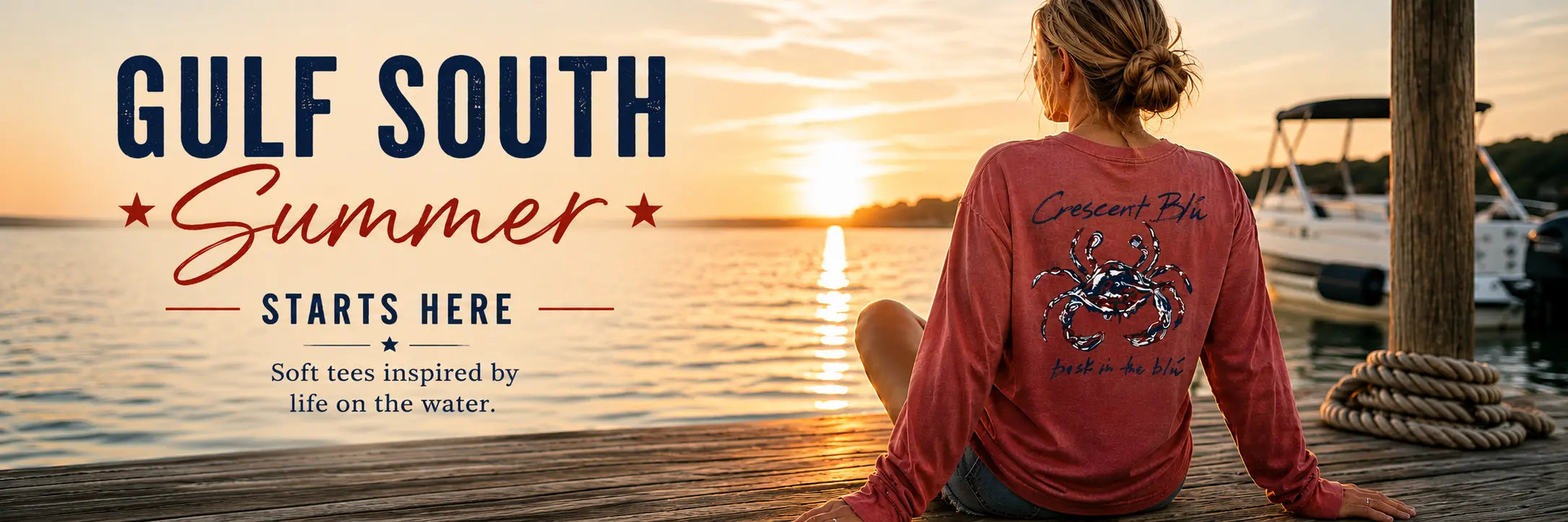 Woman sitting on a dock at sunset with wearing a red, white, and blue crab long sleeve shirt and 'Gulf South Summer' text.