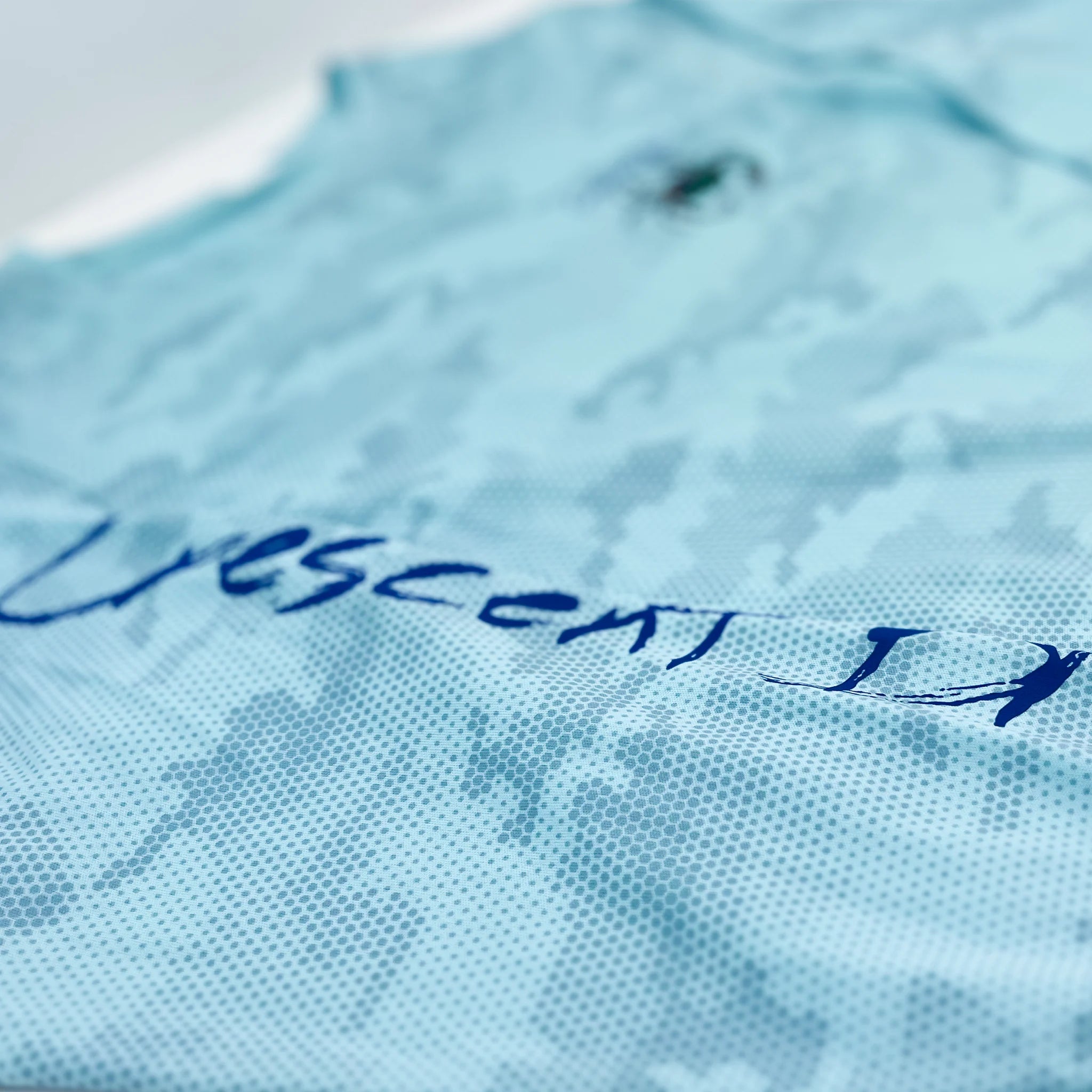 Close up of the aqua blue hex camo print with a partial view of Crescent Blu printed  the sleeve.