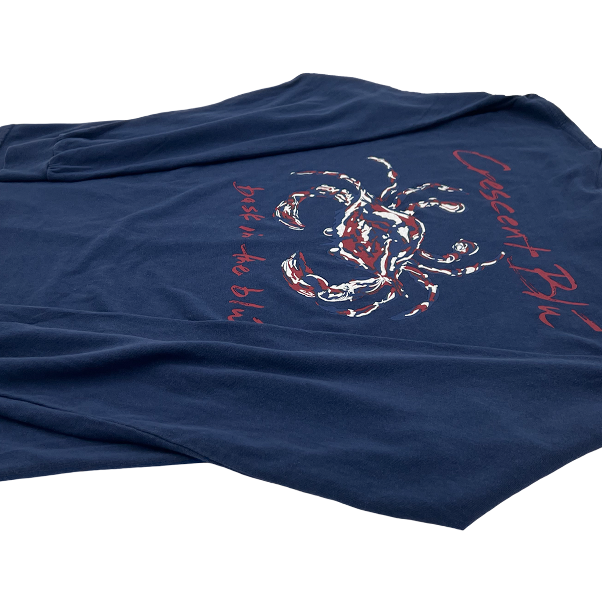 Side vide of the back of the navy long sleeve t-shirt with a Crescent Blú written in dark red above a red, white, and navy colored crab. The words, bask in the blú, are written below the crab.