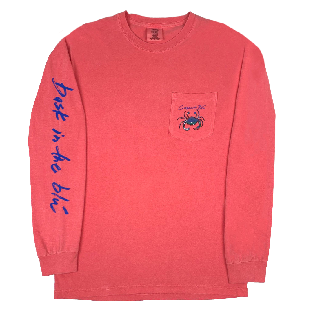 Adult t-shirt, long sleeve with pocket, with multi-colored crab logo printed on the upper left chest pocket and Bask in the Blu printed along the length of the right sleeve. Shirt is Watermelon in color. 